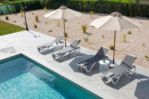a group of chairs and umbrellas next to a pool at Valley House in Vasiliki