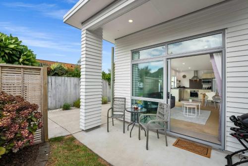 un patio con sedie e tavolo e una cucina di Sunny Seaside Retreat - Papamoa Beach a Papamoa