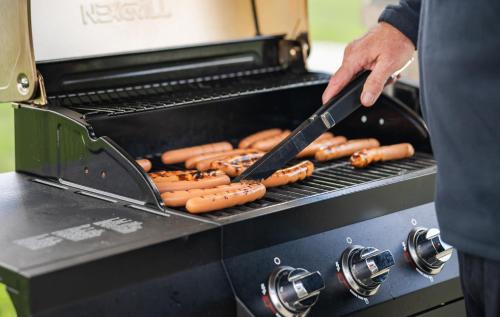 a man is cooking hot dogs on a grill at My Place Hotel-Mount Pleasant, WI in Mount Pleasant