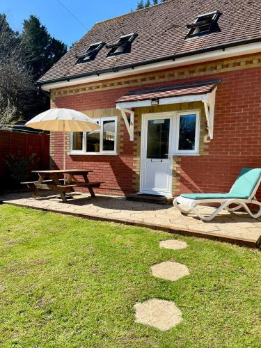 a house with a table and a bench and an umbrella at Honey Cottage in Totland