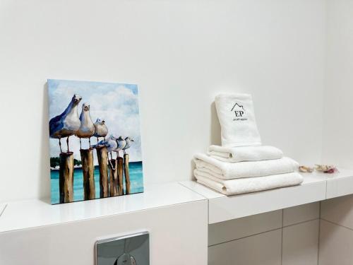 ジブヌフにあるApartament OCEAN & RIVER Sand Dunes Dziwnów z widokiem na morze i rzękę EPapartamentyのバスルーム(タオル付)が備わります。棚に絵画が飾られています。