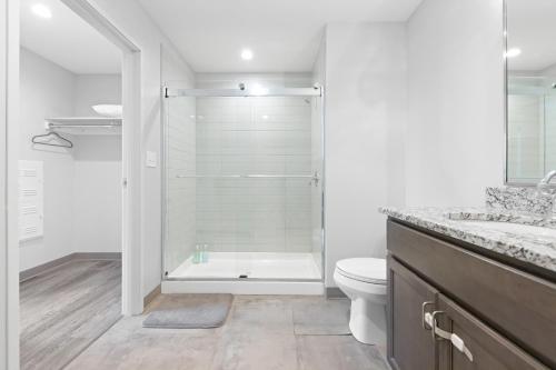 a white bathroom with a shower and a toilet at Luxe Condo in Downtown Cleveland l 2 TV's l Parking in Cleveland