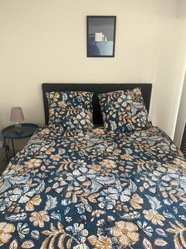 un lit avec une couette colorée et un tableau sur le mur dans l'établissement l’ Amont, à Étretat