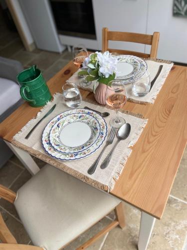 a wooden table with plates and silverware on it at Le Dolmen, charme sport et détente in Saint-Chels