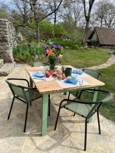 a wooden table with two chairs and flowers on it at Le Dolmen, charme sport et détente in Saint-Chels