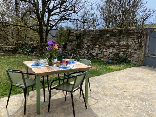 a table with chairs and a vase of flowers on it at Le Dolmen, charme sport et détente in Saint-Chels
