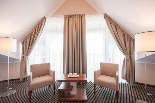 two chairs and a table in a room with windows at Hotel White in Krynica Morska