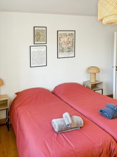 - un lit rouge avec 2 serviettes dans l'établissement App 94 m2, balcon, ascenseur, 2 ch, 4 couchages, à Aurillac