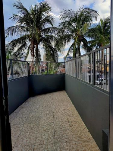 a balcony with a view of palm trees and the ocean at Kitnet pé na areia - Mirim - PG in Praia Grande