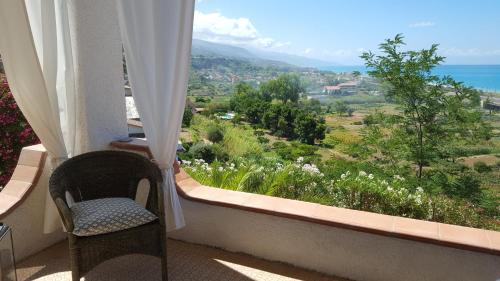 a chair sitting in a balcony with a view of the ocean at Villa Anna - Ampio appartamento con terrazza panoramica sul mare in Marina di Fuscaldo