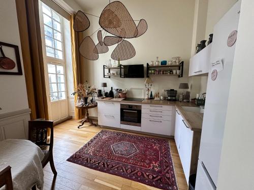 une cuisine avec des placards blancs et un tapis rouge dans l'établissement Le plumereau ensoleillé, à Tours