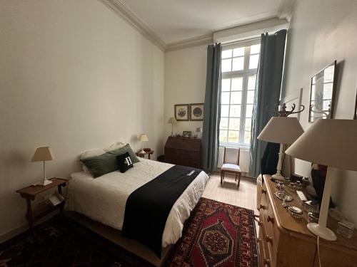 - une chambre avec un lit et un bureau avec deux lampes dans l'établissement Le plumereau ensoleillé, à Tours