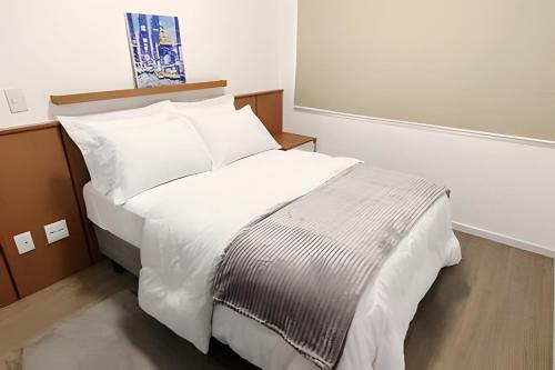 Una cama con sábanas blancas y almohadas en una habitación. en Apto c/ sacada próx Ayrton Senna, en Londrina
