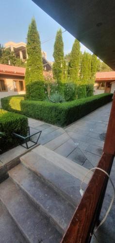 a bench in a courtyard with trees and bushes at DALLAR Guest House in Yerevan