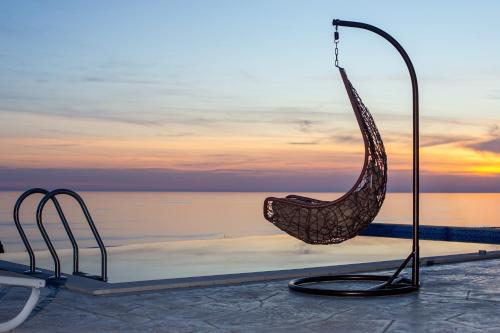 a swing chair sitting on the edge of a pool at Villa Aurora Azure - Luxury Infinity Pool Resort in Katun