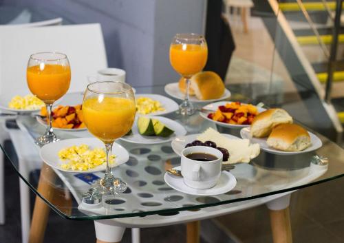 ein Tisch mit Tellern voller Essen und Gläsern mit Orangensaft in der Unterkunft Aparthotel Costal Sol Tacna in Tacna