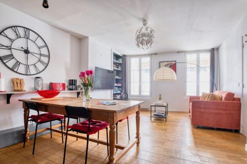 - un salon avec une table et une horloge murale dans l'établissement Bel appt 42m² au cœur de Trouville 2mns de la mer, à Trouville-sur-Mer