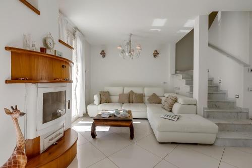 Una sala de estar blanca con un sofá y un televisor. en Casa Patino - Happy Rentals, en Torre del Lago Puccini