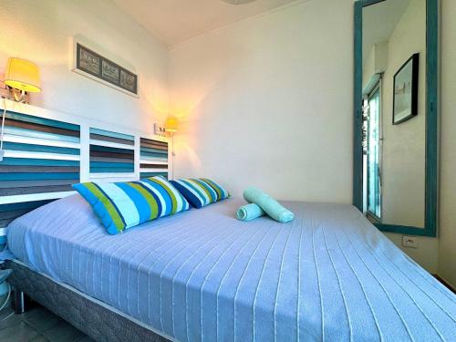 a bedroom with a large bed with blue pillows at Les Petits Bateaux-Parking privé-Terrasse in La Grande-Motte