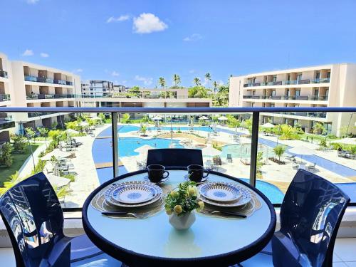 a table on a balcony with a view of a pool at Malia Beach Experience - Muro Alto - Vista piscina central - Flat 205C in Ipojuca