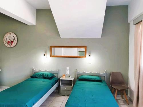 a bedroom with two beds and a clock on the wall at Valentino Studio Kalymnos in Kalymnos