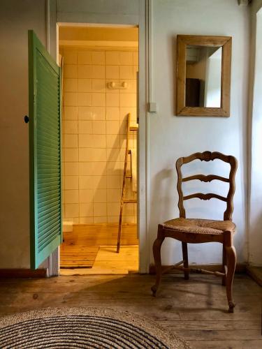 une chaise en bois dans une chambre avec salle de bains dans l'établissement Les Volets Verts, à Miraval-Cabardès