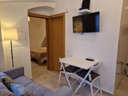 a living room with a table and a tv on a wall at Casa da Judiaria in Évora