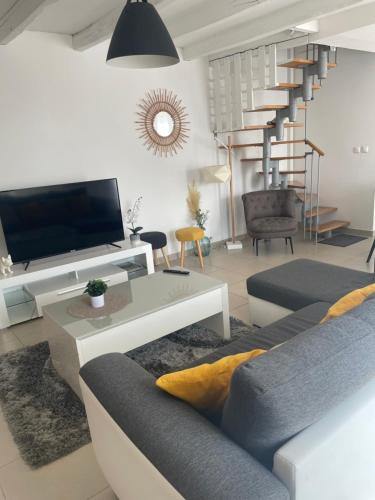 a living room with a couch and a tv at Escapade poitevine - Maison climatisée avec 3 Ch - 4 min Futuroscope et Aquascope in Chasseneuil-du-Poitou