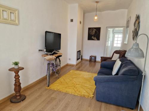 a living room with a blue couch and a tv at Casa Gil Vicente in Évora