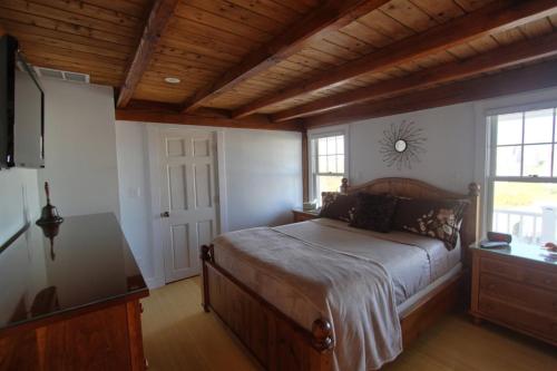 a bedroom with a bed and a dresser and a television at West Yarmouth - Luxury Oceanfront Vacation Home in Yarmouth