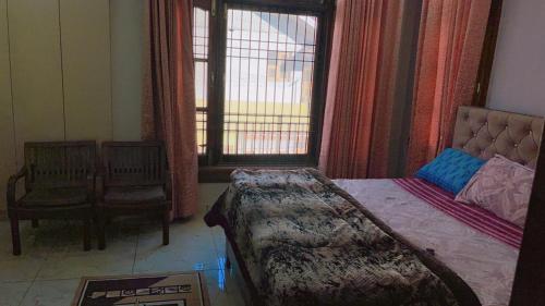a bedroom with a bed and a chair and a window at Dhauladhar Vista in Pālampur