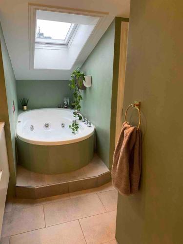 a bathroom with a bath tub with a skylight at Stylish Grünerløkka penthouse with rooftop terrace in Oslo