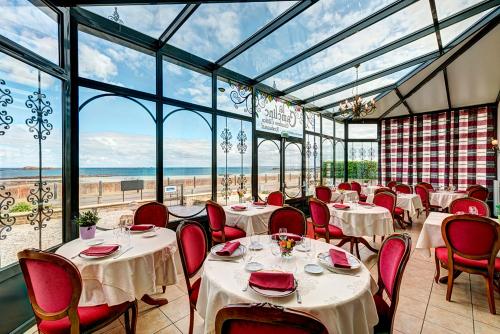 un restaurant avec des tables et des chaises blanches et des fenêtres dans l'établissement La Cameline, à Plougasnou