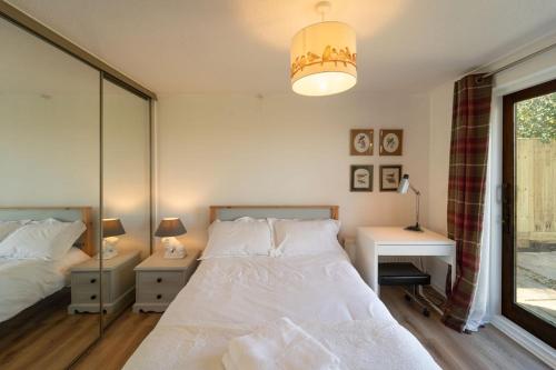 a bedroom with two beds and a desk and a window at Bumble Bee Bungalow Serviced Accommodation in Witney