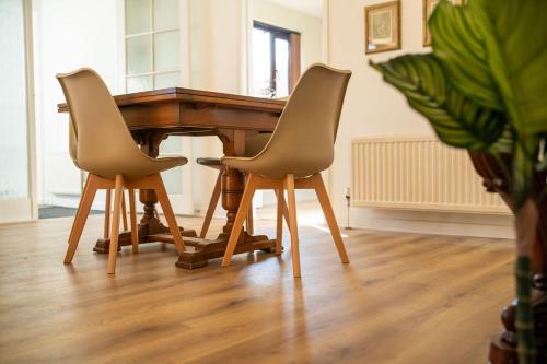 a wooden piano with two chairs in a living room at Bumble Bee Bungalow Serviced Accommodation in Witney