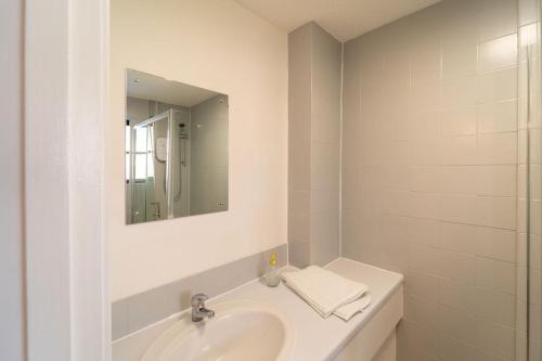 a white bathroom with a sink and a mirror at Bumble Bee Bungalow Serviced Accommodation in Witney