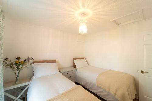 a bedroom with two beds and a vase of flowers at Bumble Bee Bungalow Serviced Accommodation in Witney
