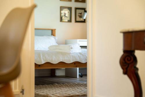 a bedroom with a bed with white sheets and towels at Bumble Bee Bungalow Serviced Accommodation in Witney
