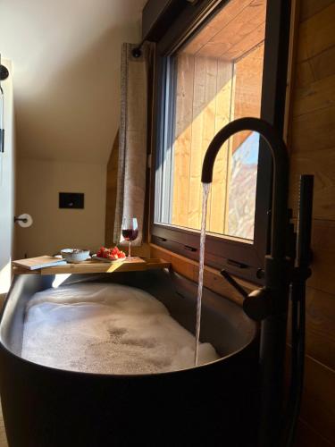d'une baignoire avec de l'eau provenant d'une fenêtre. dans l'établissement Chalet Cimebleu SPA & Sauna, à Basse-sur-le-Rupt
