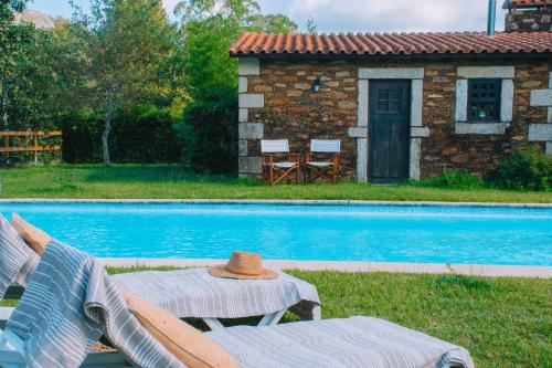a hat sitting on a table next to a pool at Just Like Home - Casa da Telheira in Caminha