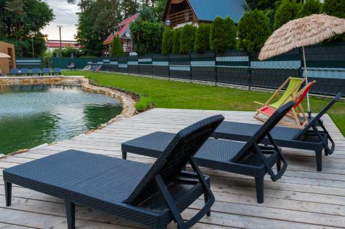 two chairs and a table next to a swimming pool at ZIEMIA-OGIEŃ Apartamenty Mazurska Kraina Narie in Bogaczewo