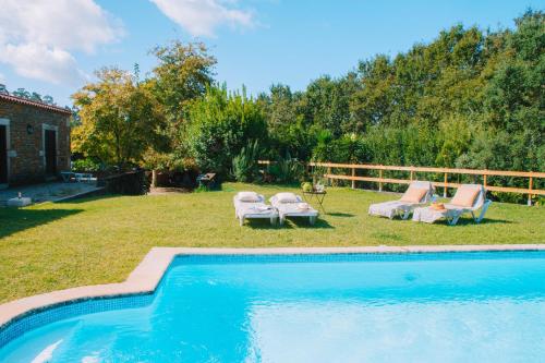 a swimming pool in a yard with two lounge chairs at Just Like Home - Casa da Telheira in Caminha