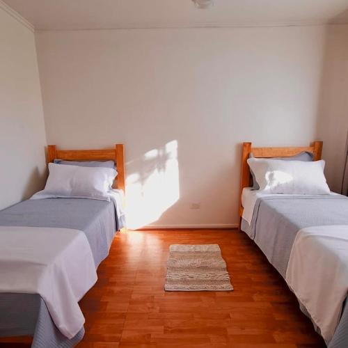 two beds in a room with a rug on the floor at Casa Terracota in Chillán
