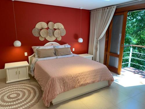 a bedroom with a bed and a red wall at Chalé Banho de Floresta Atibaia Clube de Montanha in Atibaia