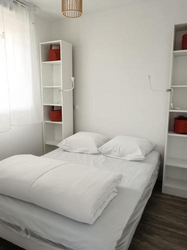 ein Bett mit weißen Laken und Kissen in einem Schlafzimmer in der Unterkunft Les Hauts de Balaruc THERMES in Balaruc-les-Bains