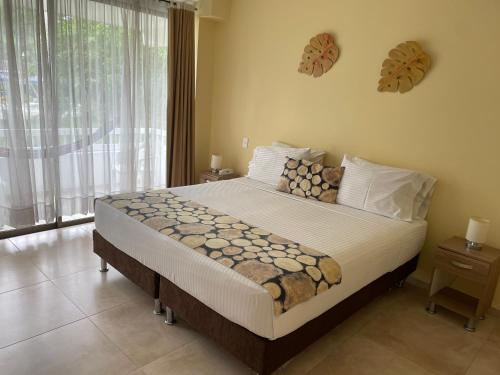 a bedroom with a large bed and a large window at Hotel Hacienda El Diamante in Villeta