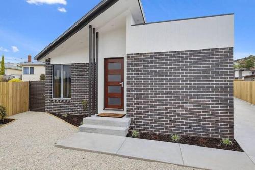a brick house with a brown and white door at The Villa at 165 Contemporary apartment in Warrane
