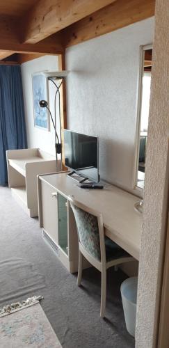 escritorio con ordenador y silla en una habitación en Bären-Krattigen, en Krattigen
