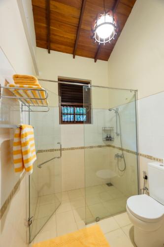 a bathroom with a glass shower and a toilet at Petit Paradis Hiriketiya in Hiriketiya
