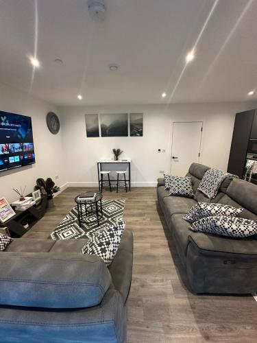 a living room with two couches and a flat screen tv at Panoramic Private Room and Bathroom in a Modern Apartment in Croydon